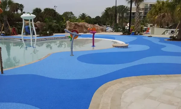 commercial-pooldeck-pebbleflex-blog Commercial splash pad with poured-in-place rubber safety surfacing, custom blue design, and interactive water features.