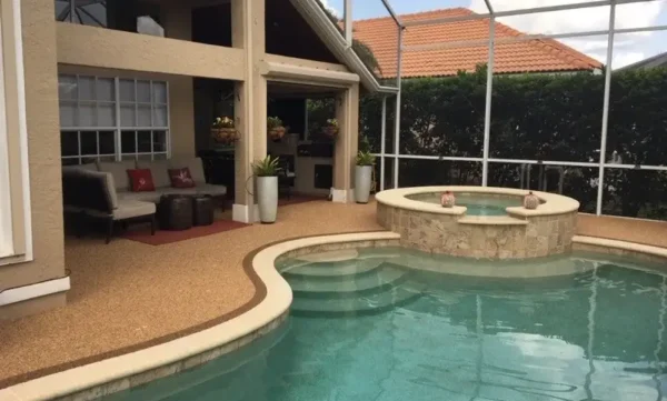residential-epoxystone-pooldeck-blog Residential pool deck with seamless poured-in-place rubber surfacing, slip-resistant finish, and integrated spa in a screened lanai.