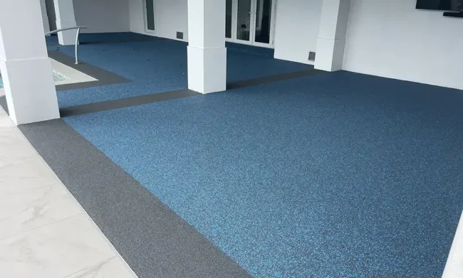 residential-flexirock-pooldeck-blog Covered patio with seamless poured-in-place rubber surfacing in blue tones, featuring a slip-resistant, low-maintenance finish.