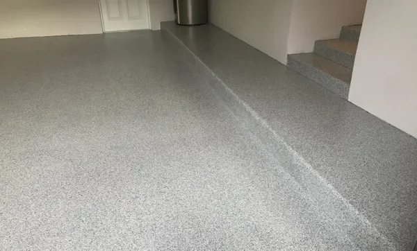 Epoxy flake garage floor coating with seamless finish and raised step in a residential interior space.