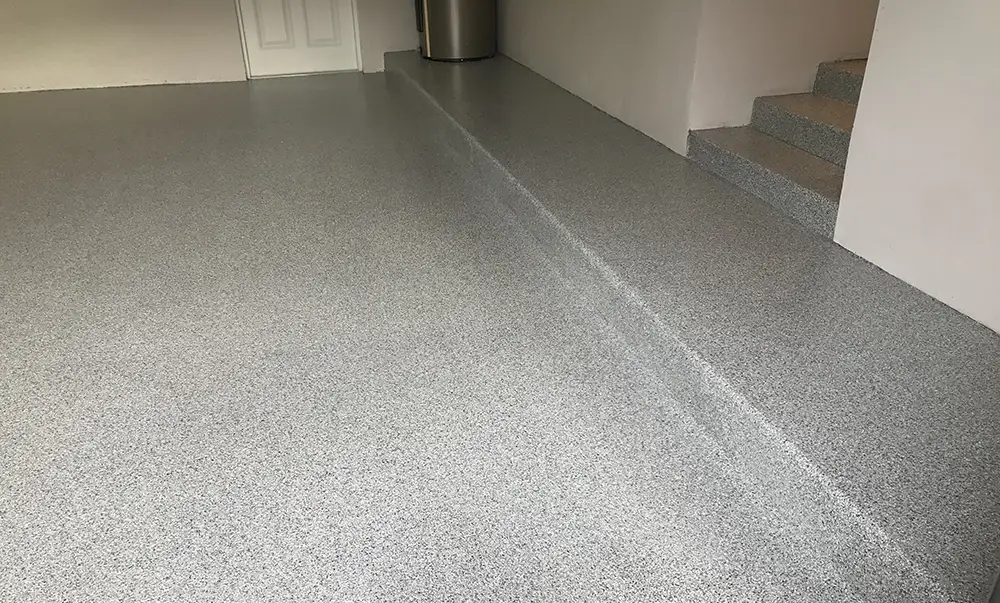 Epoxy flake garage floor coating with seamless finish and raised step in a residential interior space.